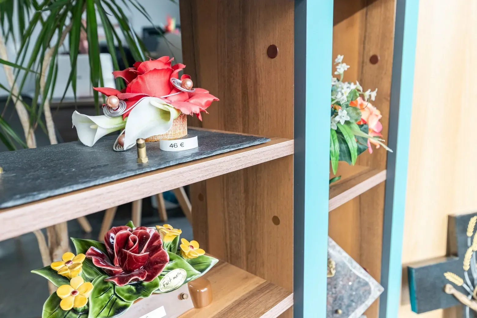 Présentoir en bois exposant des compositions florales artificielles et céramiques funéraires