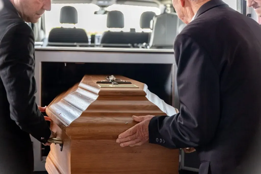 Transport du cercueil en bois par des porteurs lors d'un convoi funéraire
